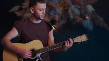 Erkek müzisyen akustik gitar çalıyor. Gitarist konserde sahnede klasik gitar çalar.