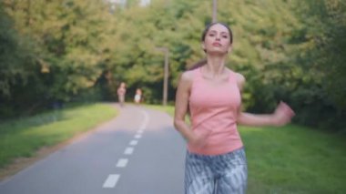 Atletik kadın, yaz günü parkta koşuyor. Beyaz kadın, spor kıyafetleriyle koşuyor.