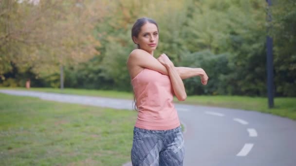 Женщина-бегун вытягивает руки перед запуском летнего парка — стоковое видео