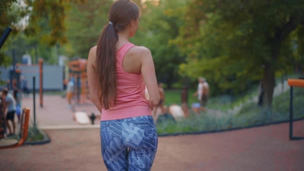 Sportowa kobieta stojąca letni dzień na boisku odpoczynku po ciężkim treningu pić wodę plastikowa butelka Widok z tyłu średni pędu — Wideo stockowe