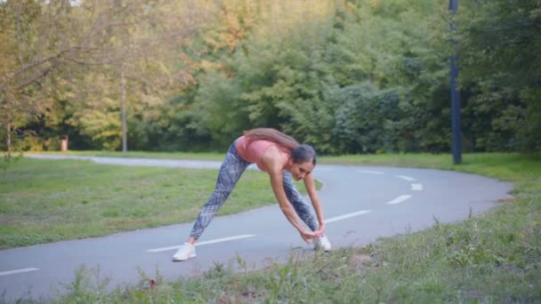 Kobieta biegacz rozciągając ramiona przed bieganiem letni park — Wideo stockowe