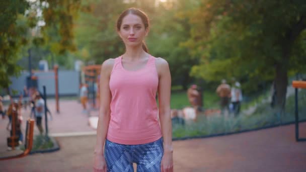 Sebevědomí atletická žena stojící sportovní hřiště v letním parku hledá kameru Kavkazský sportovní krásná žena portrét — Stock video