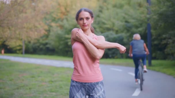 Kobieta biegacz rozciągając ramiona przed bieganiem letni park — Wideo stockowe