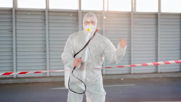 Muž, pracovník tančící hraniční čáru varovné znamení dezinfikuje, stříkající chemikálie na povrchu proti koronaviru. Sanitární opatření na veřejném místě během karantény — Stock video