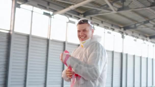 Мужчина носит белый защитный общий снимает защитную ленту смеется счастливым, потому что карантин закончился Конец пандемии концепции — стоковое видео