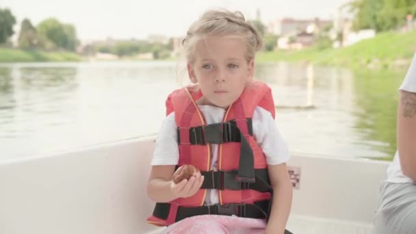 Klein meisje gekleed leven vest rit plezier boot op de stad rivier Zonnige zomerdag Kaukasische vrouwelijke kind met moeder zwemmen op de boot — Stockvideo