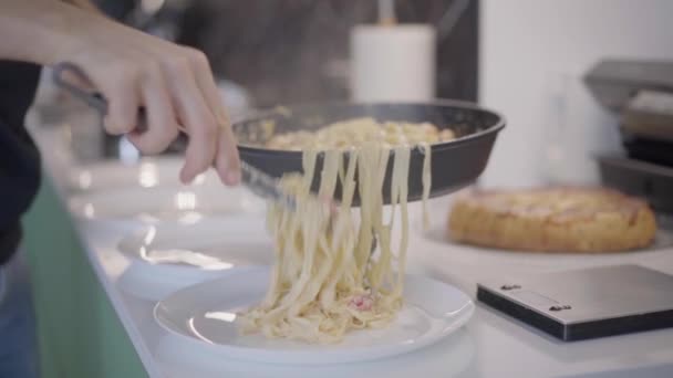 Pasta Carbonara mempersiapkan panci. Man tangan dekat menempatkan di piring spaghetti dengan susu udang dan krim — Stok Video