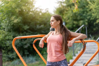 Kendine güveni tam atletik bir kadın yaz parkında durmuş beyaz tenli sporcu güzel kadın portresi sağlıklı yaşam tarzı konseptine bakıyor.