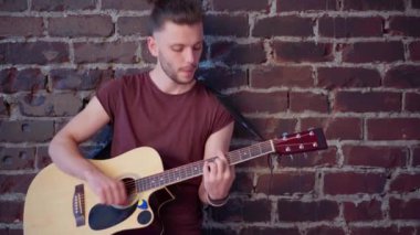 Akustik gitarı olan, tuğla duvara karşı müzik çalan, şarkı söyleyen, hayatın tadını çıkaran adam.