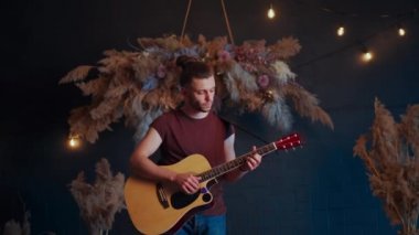 Erkek müzisyen akustik gitar çalar. Gitarist konserde sahnede klasik gitar çalar.