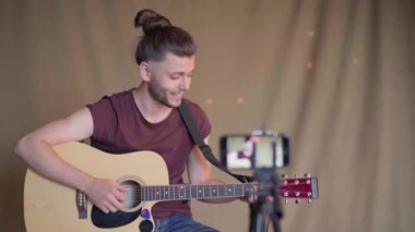 Öğrenciler için gitar dersleri kaydeden bir adam. Online gitar kursları. Uzaklık öğrenme kavramı