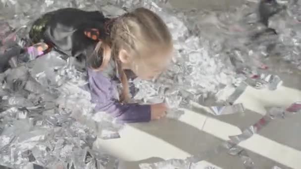 Kleines Mädchen, das an ihrem Geburtstag Spaß hat, sammelt glänzendes Konfetti vom Boden und löst positive Emotionen aus — Stockvideo