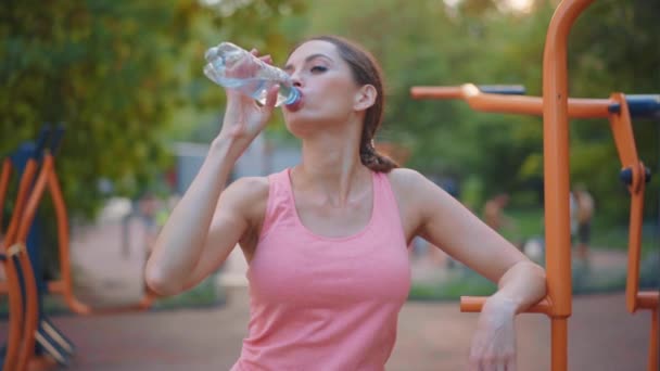 辛勤训练后站在运动场上的女运动员喝了水、塑料瓶、中枪 — 图库视频影像