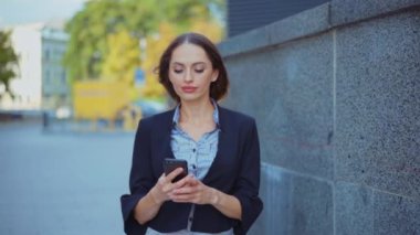 İş kadını akıllı telefon mesajları kullanıyor şirket ofisinde yürüyor cep telefonuna mesaj yazıyor.