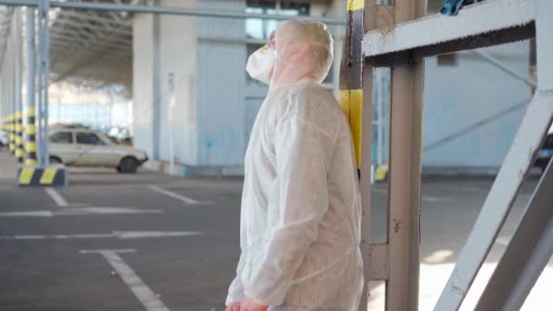 Verzweifelte Krankenpfleger in weißen Schutzanzügen. Müder kaukasischer Arzt kauert während Coronavirus-Pandemie in Depressionen — Stockvideo