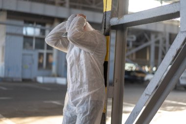 Beyazlar içinde ümitsiz bir sağlık çalışanı. Kafkasyalı yorgun doktor, koronavirüs salgını sırasında depresyondan başını tutuyor.