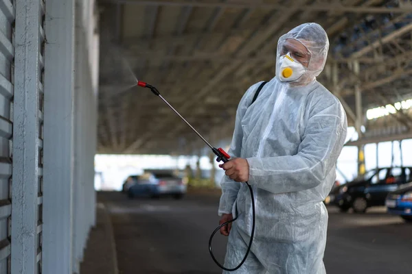 Koruyucu giysi giyen işçiler dezenfekte ekipmanları halka açık bir yerde park ediyorlar. Genel olarak dezenfektan güvenliği ve solunum maskesi Covid salgını önleyici tedbirler