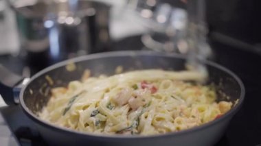 Tavada hazırlanmış Carbonara makarnası. Adam eli karides sütlü ve kremalı spagetti pişiriyor.