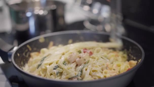 Carbonara pasta förbereder på pan. Man hand närbild matlagning spaghetti med räkor mjölk och grädde — Stockvideo