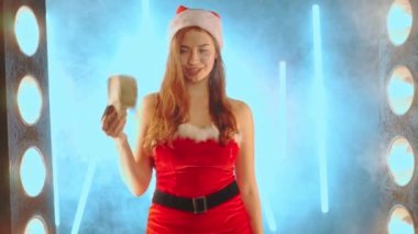 Noel tatili indirimi konsepti Noel Baba kostümü giymiş kadın Noel Baba şapkası giymiş fanlar gibi dalgalanırken aydınlanmış neon arka plan