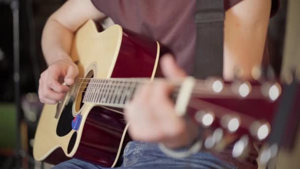 Pemuda tampan bermain gitar akustik duduk kursi dekat menembak — Stok Video