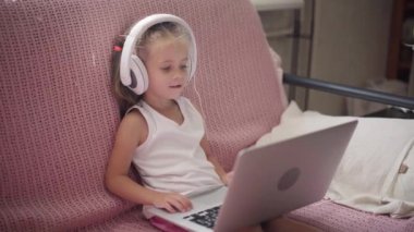 Kulaklıkla Koltukta oturan küçük kız. Müzik dinle. Laptop Ev İçi Eğlenceli Kafkas Kadın Çocuk Teknolojisi Modern Çocuklar Mutlu Çocukluk 