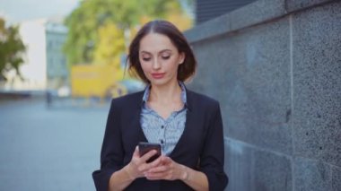 İş kadını akıllı telefon mesajları kullanıyor şirket ofisinde yürüyor cep telefonuna mesaj yazıyor.