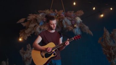 Erkek müzisyen akustik gitar çalar. Gitarist konserde sahnede klasik gitar çalar.