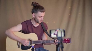 Öğrenciler için gitar dersleri kaydeden bir adam. Online gitar kursları. Uzaklık öğrenme kavramı