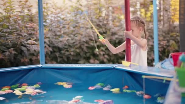 Niño pescador captura de plástico juguete pescado en la piscina Parque de atracciones Día de verano — Vídeos de Stock