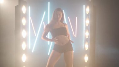Arka planda sis dumanı içinde dans eden sanatçı genç bir kadın. Kendine güvenen zarif beyaz kadın dansçı modern performansı bale hareketleri ile prova ediyor.