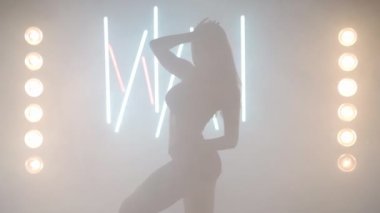 Arka planda sis dumanı içinde dans eden sanatçı genç bir kadın. Kendine güvenen zarif beyaz kadın dansçı modern performansı bale hareketleri ile prova ediyor.