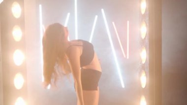 Arka planda sis dumanı içinde dans eden sanatçı genç bir kadın. Kendine güvenen zarif beyaz kadın dansçı modern performansı bale hareketleri ile prova ediyor.