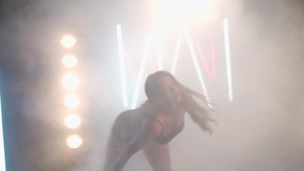 Artistica giovane donna che balla in nebbia retroilluminata fumo all'interno. Fiduciosa ballerina caucasica graziosa che prova prestazioni moderne con movimenti di balletto — Video Stock