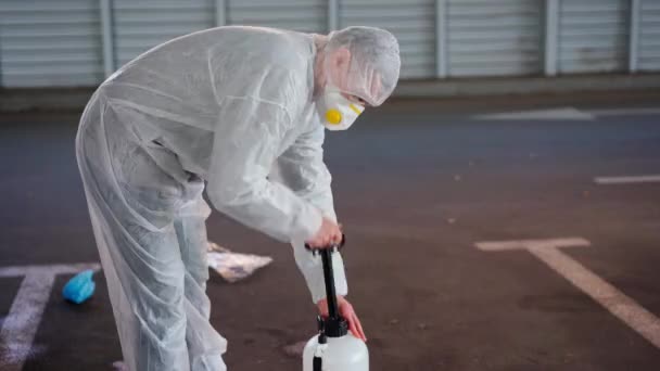 Man geklede witte beschermende overalls spuiten oppervlak antibacteriële reiniger spuit tijdens quarantaine — Stockvideo