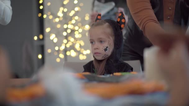 Kleines Mädchen dekoriert Zuckerguss handgemachte Halloween-Plätzchen gekleidet Halloween Karneval Kostüm mit Hörnern — Stockvideo
