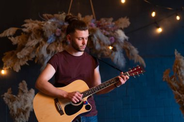 Erkek müzisyen akustik gitar çalıyor. Gitarist konserde klasik gitar çalıyor. Yakışıklı genç hippi gitarist özel bir parti veriyor. Uzun saçlı, orta boy.