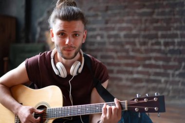 Akustik gitar çalan yakışıklı genç adam oturma odasında beyaz tenli erkek hippi kulaklıkçı şarkı söyleyen, müzik dinleyen, yaratıcı, genç adamı rahatlatan, orta yaşlı adam.