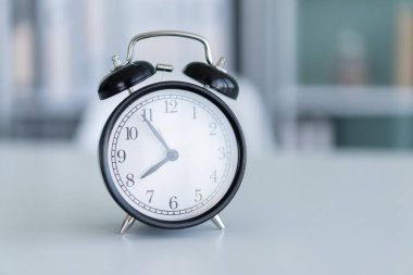 Alarm saati beyaz masada duruyor. Arka plan temiz. Sabah Saati konsepti.