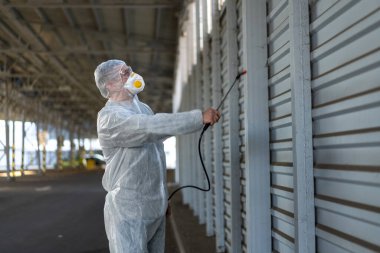 Koruyucu giysi giyen işçiler dezenfekte ekipmanları halka açık bir yerde park ediyorlar. Genel olarak dezenfektan güvenliği ve solunum maskesi Covid salgını önleyici tedbirler