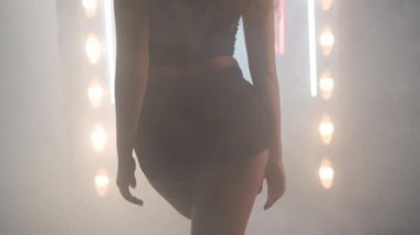 Arka planda sis dumanı içinde dans eden sanatçı genç bir kadın. Kendine güvenen zarif beyaz kadın dansçı modern performansı bale hareketleri ile prova ediyor.