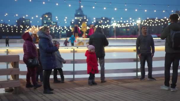 Ukrajna, Harkov December 2021 Karácsonyi korcsolyapálya a város főterén egyesek korcsolyáznak mások nézik, ahogy valaki sétáló párokat fényképez. — Stock videók