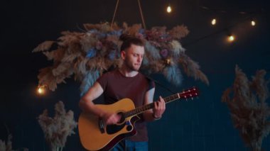 Erkek müzisyen akustik gitar çalıyor. Gitarist konserde sahnede klasik gitar çalar.