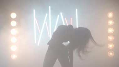 Arka planda sis dumanı içinde dans eden sanatçı genç bir kadın. Kendine güvenen zarif beyaz kadın dansçı modern performansı bale hareketleri ile prova ediyor.
