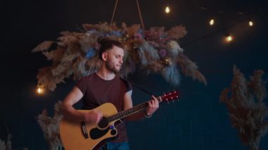 Erkek müzisyen akustik gitar çalıyor. Gitarist konserde sahnede klasik gitar çalar.