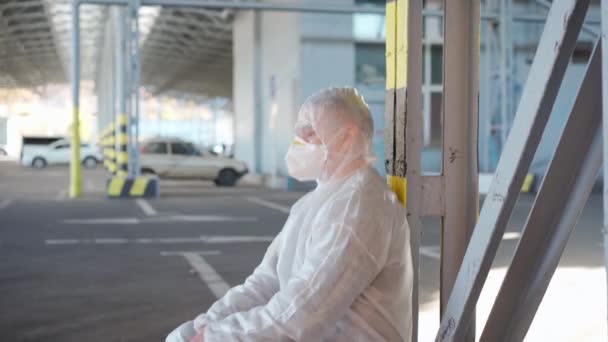 Zoufalý zdravotnický pracovník v bílých kombinézách. Unavený muž běloch lékař chytí jeho hlavu krčí v depresi během pandemie koronaviru — Stock video