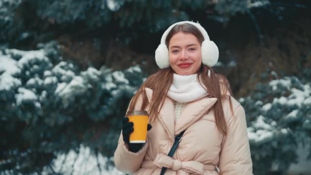 Kadınlar dışarıda kahve içer. Kış günü, beyaz bir kadın elinde kahveyle ladin ağacına çıkıyor. — Stok video