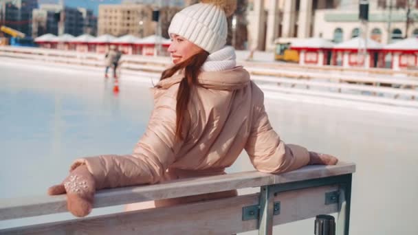Wanita muda tersenyum berseluncur es di luar arena es pusat kota di hari libur Natal, aktif liburan musim dingin di hari yang cerah hangat. Efek genggam. Peluncur es wanita amatir kaukasia — Stok Video
