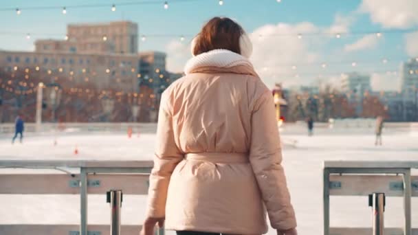 クリスマス休暇、暖かい晴れた日にアクティブな冬のレジャーでアイスリンク中央市広場の外の若い笑顔の女性のアイススケート。手押し効果。アマチュア白人女性アイススケーター — ストック動画