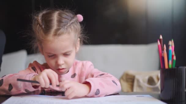 Kind tekening slijpen potloden zitten op tafel midden schieten. Blank vrouwelijk meisje tekent met gekleurde potloden. Vrouwelijke kind doet huiswerk — Stockvideo